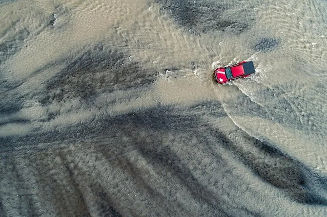 Vista aérea de una pickup roja de Arctic Trucks sobre arena negra