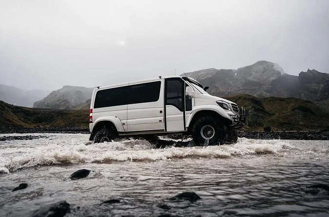 A white van-style 4x4 crossing a river