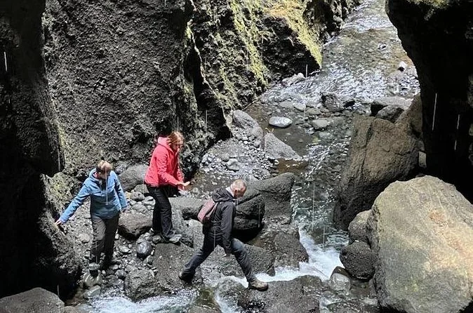 People walking through a shallow stream inside a narrow gorge
