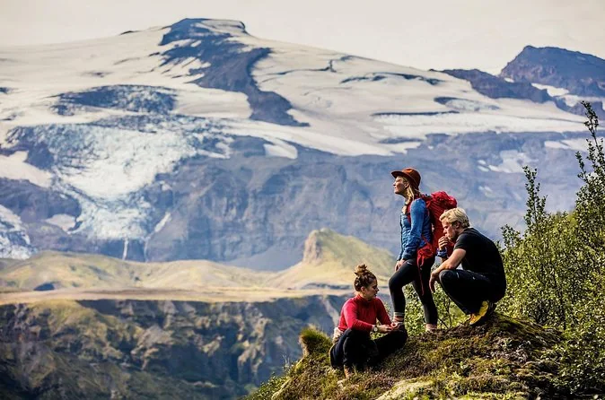 Hikers on a mossy knoll with a glacier behind