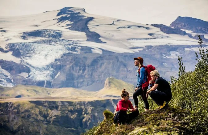 Hikers on a mossy knoll with a glacier behind